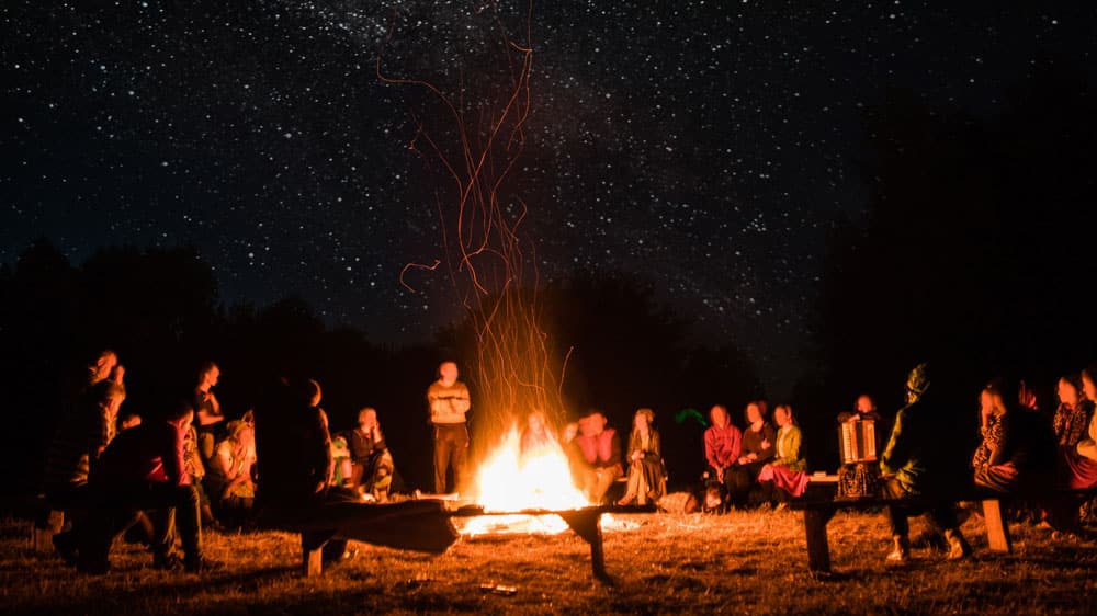 group of wiccans gathered around a Beltane holiday bonfire during a beltane ceremony