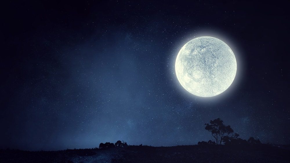 A radiant full moon over a nighttime landscape