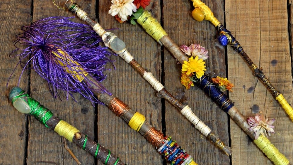 An assortment of wands that are decorated with colorful threads, crystals, and flowers