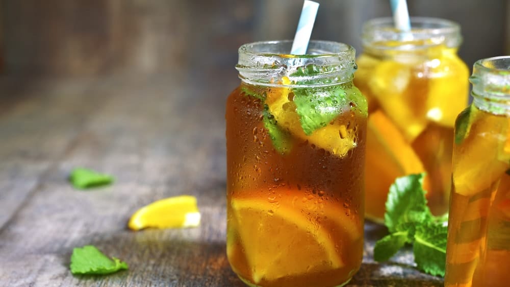 a few jars of cold sweet tea with lemon wedges and mint leaves