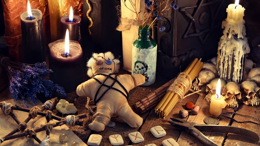 A Hoodoo altar featuring candles, a doll, lavender, runes, candles and more