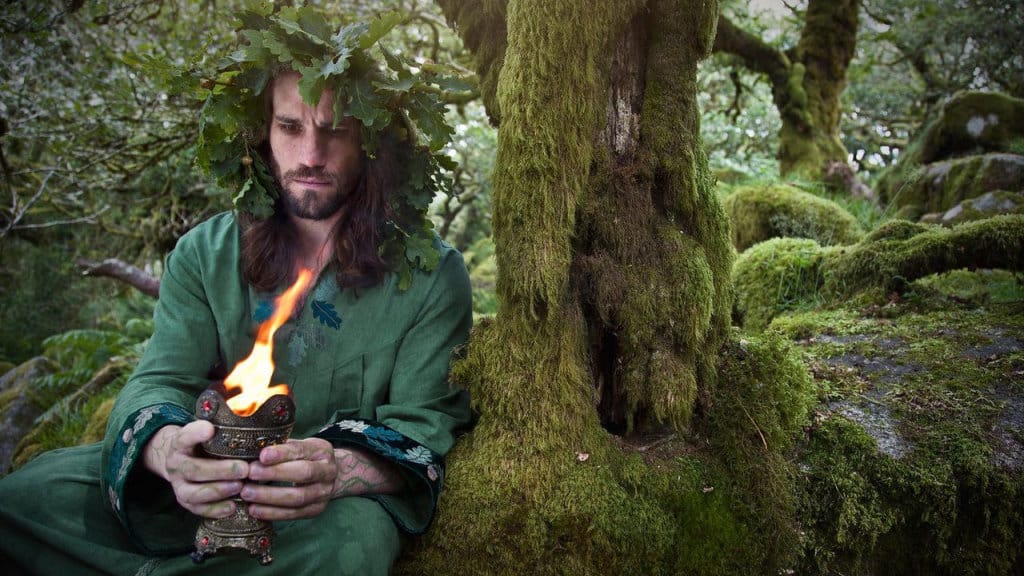 A male green witch performing a ceremony in the forest