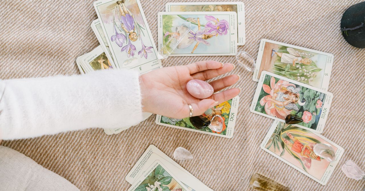 Pink Crystal on a Person's Hand above Tarot Desk