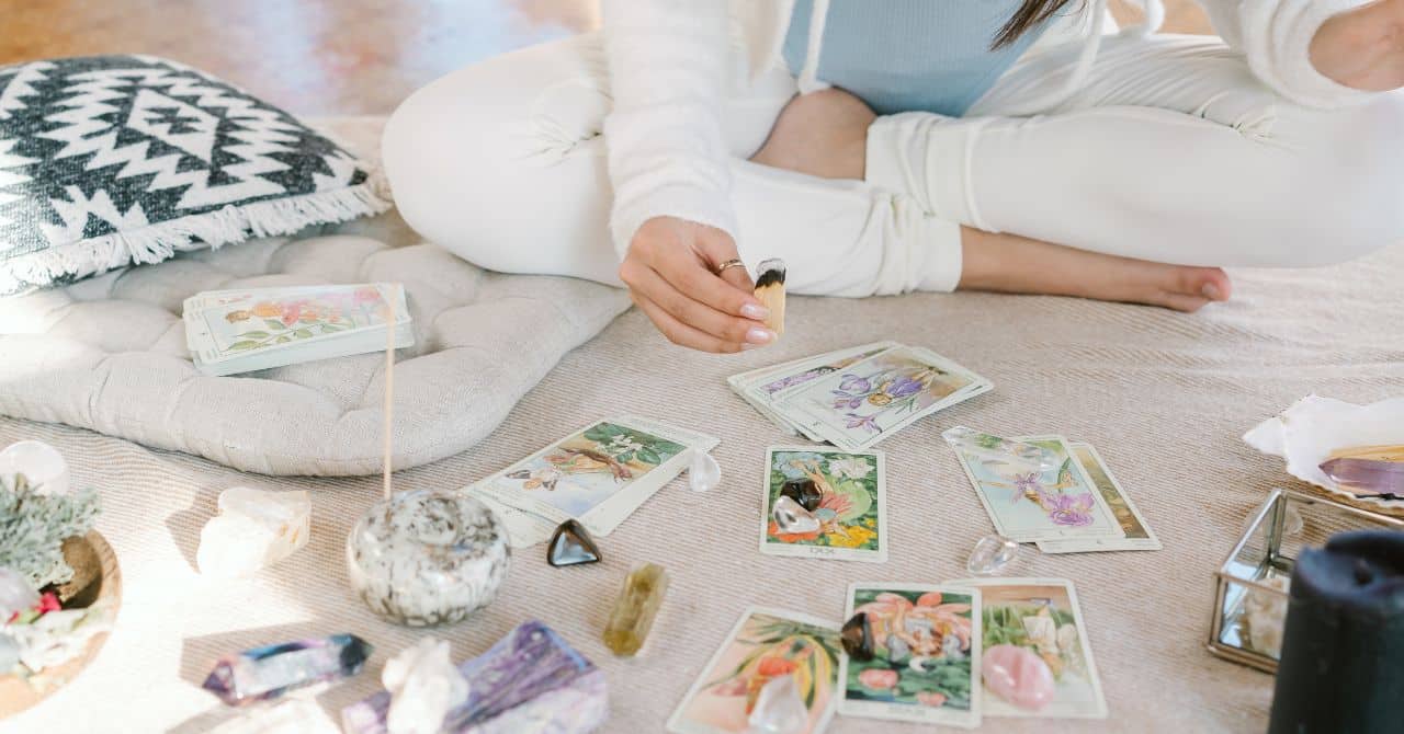 Person Holding a Burning Smudge Stick above a Tarot Deck
