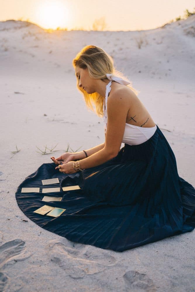 Woman Sitting On Sand With Tarot Cards On Her Skirt