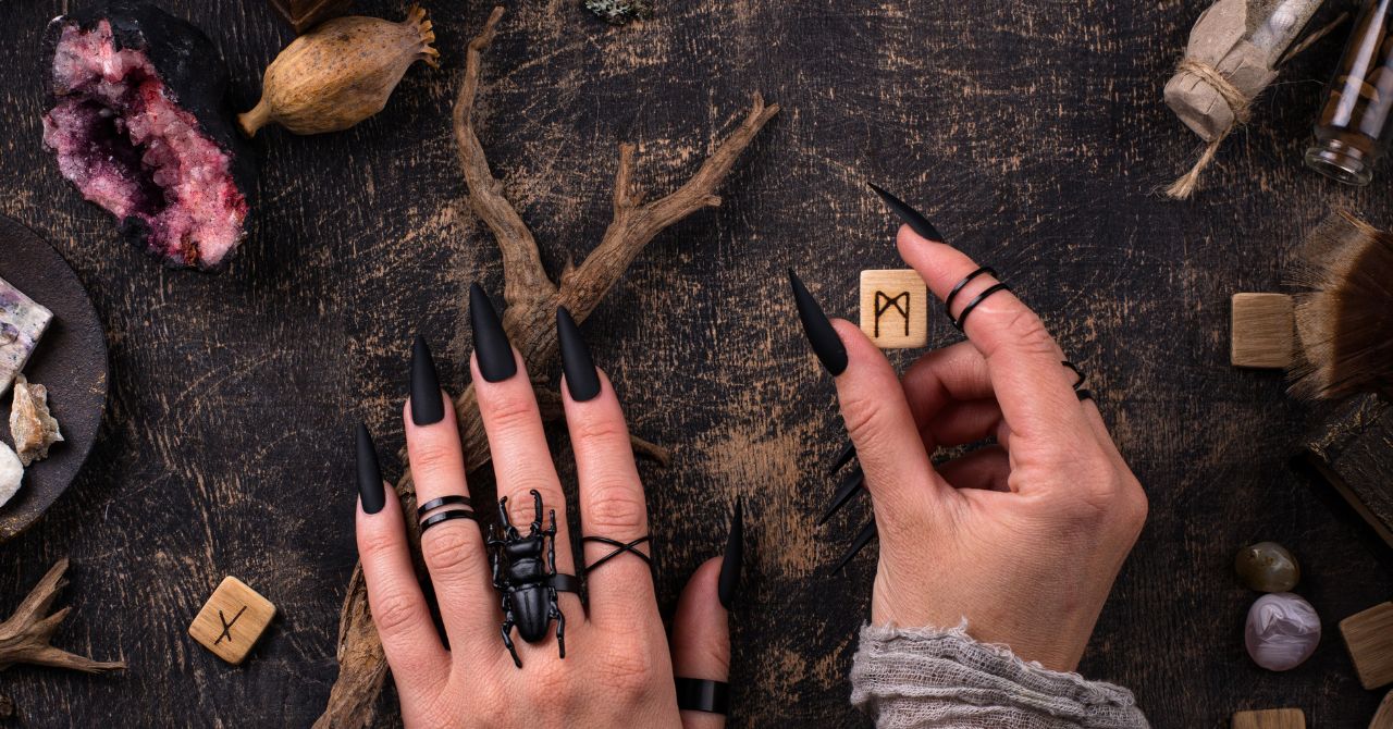 Hands, with long black nails, holding a rune