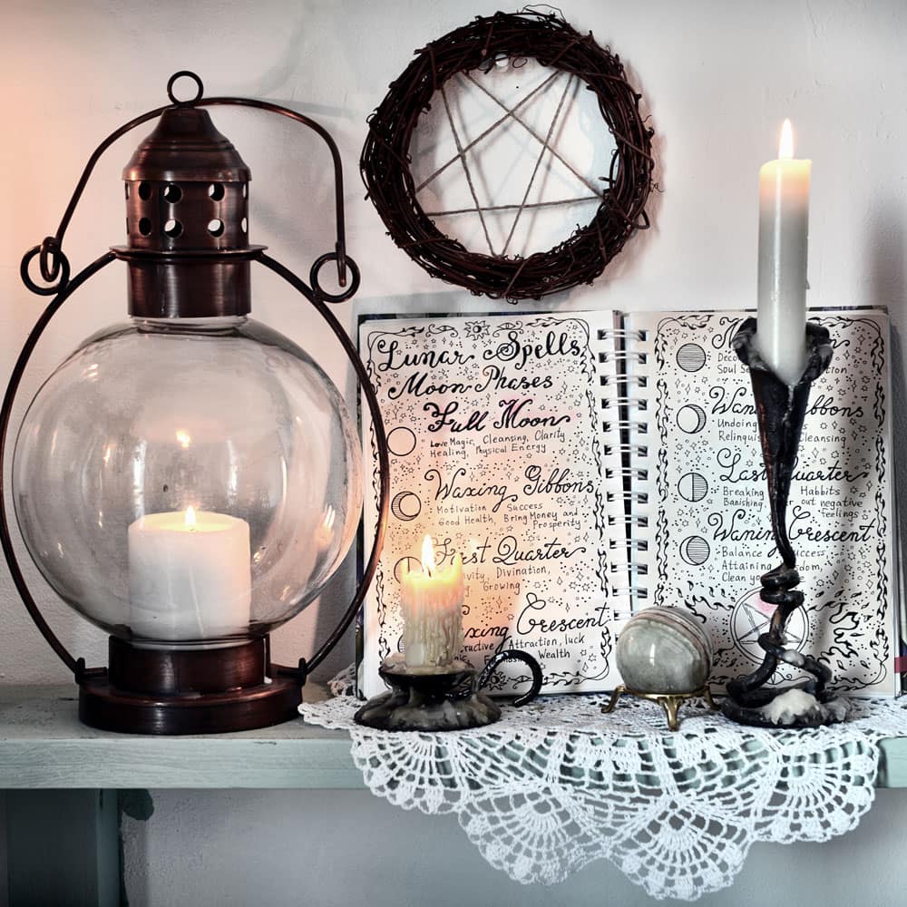 Book of Shadows open to a page of lunar spells with with candles and a pentagram wreath