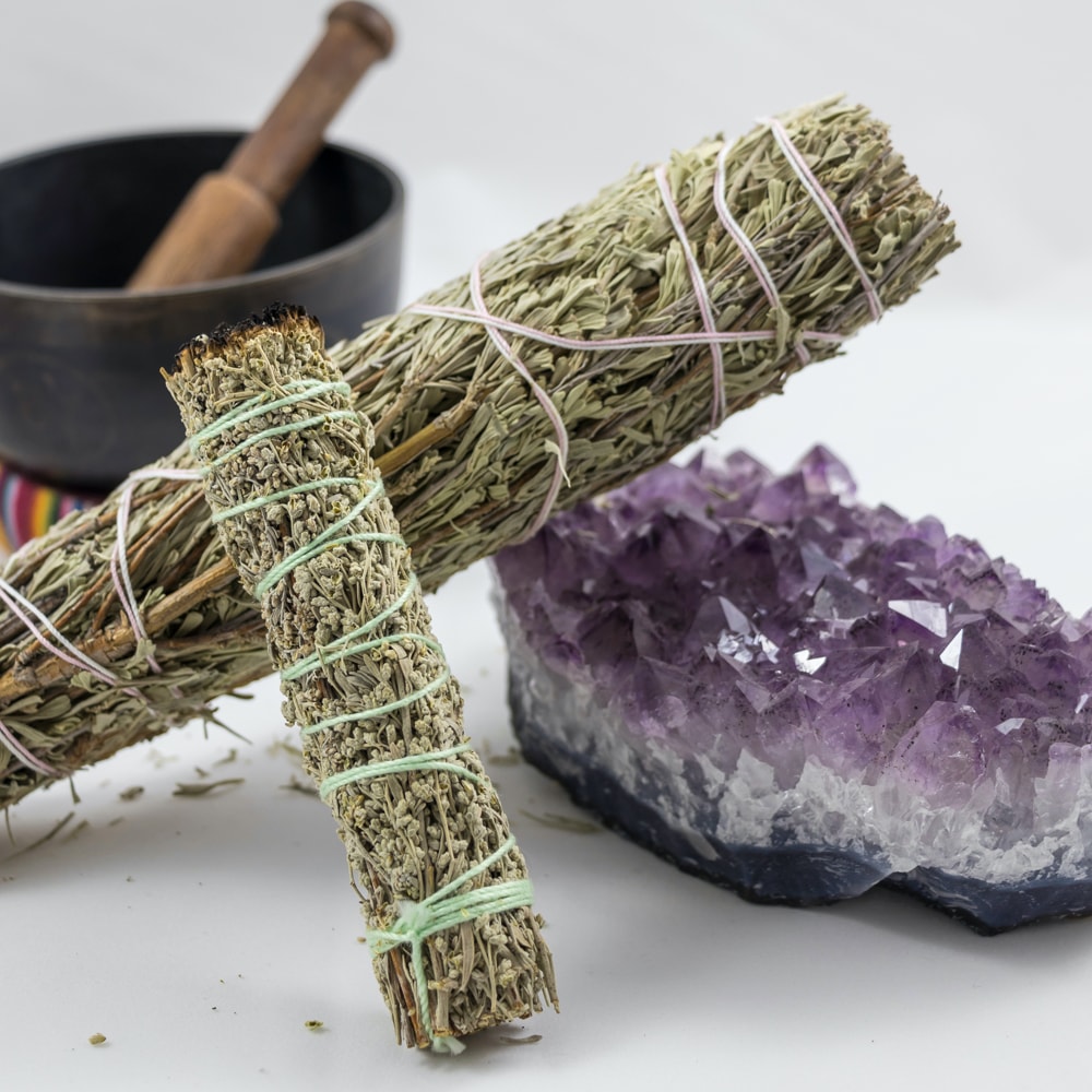 Bundles of sage with a purple geode crystal and a mortar and pestle