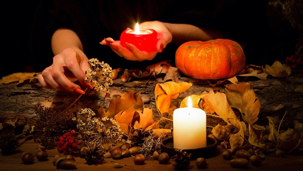 A Samhain scene featuring candles, acorns, leaves, and a pumpkin