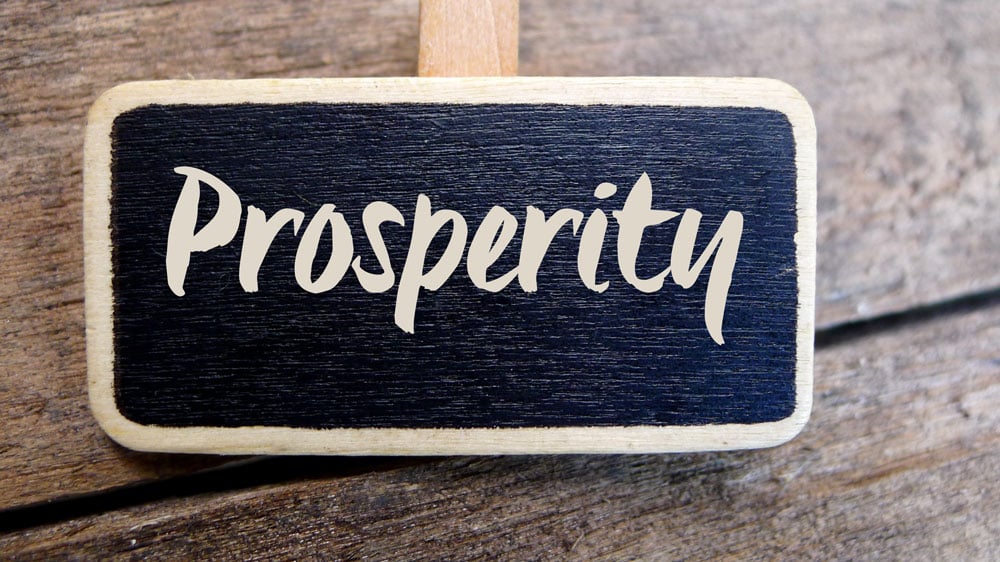 A painted wooden sign that says prosperity