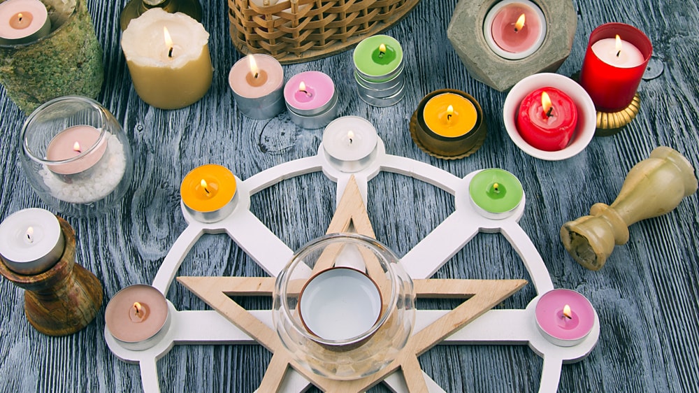 A beautiful assortment of different colored candles on and around a decorative Wiccan candle holder