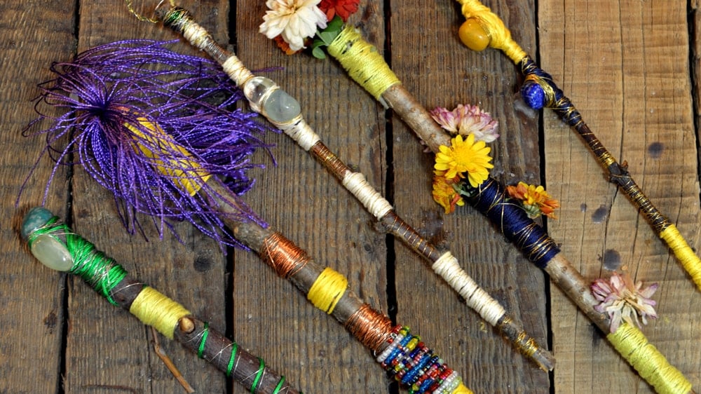 An assortment of wands that are decorated with colorful threads, crystals, and flowers