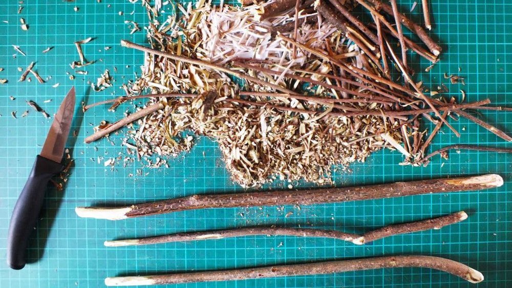 Twigs being carved into wooden wands with a knife