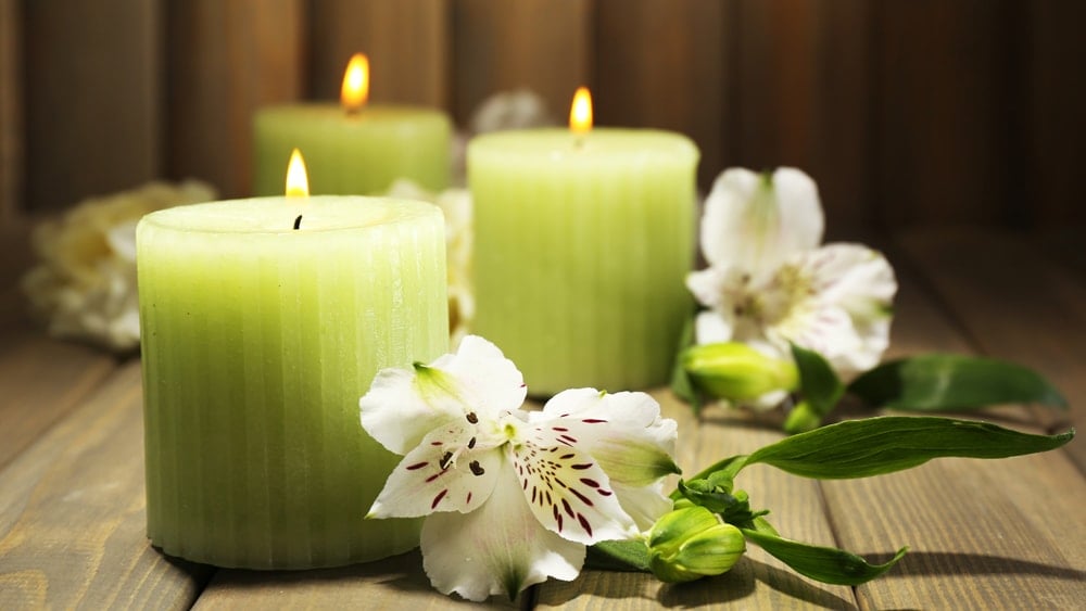 Green candles and white flowers with purple spots with a wooden background