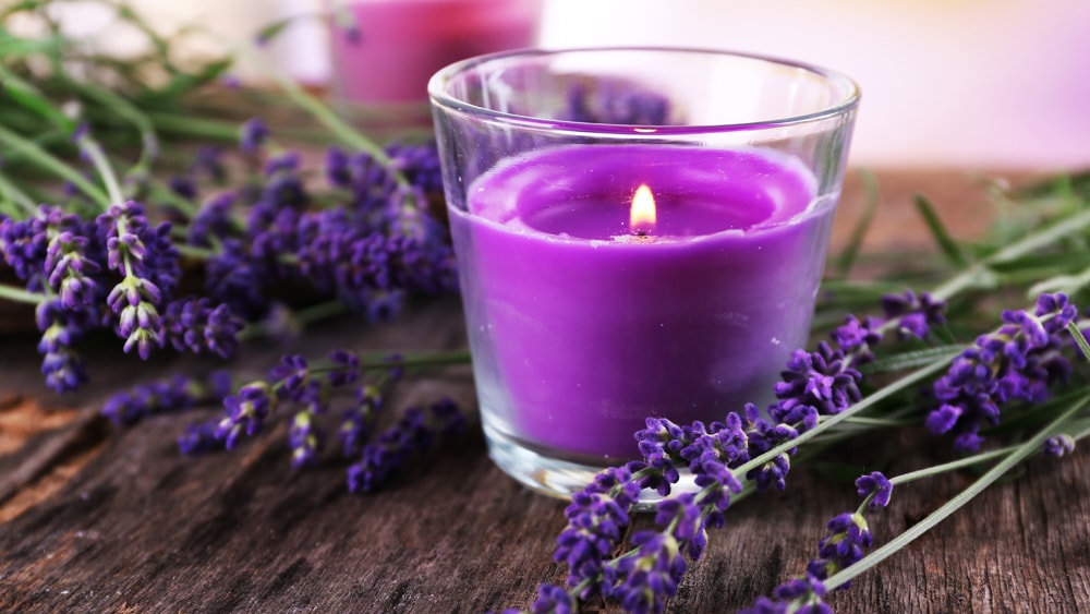 Purple candle and sprigs of lavender on a wooden table top