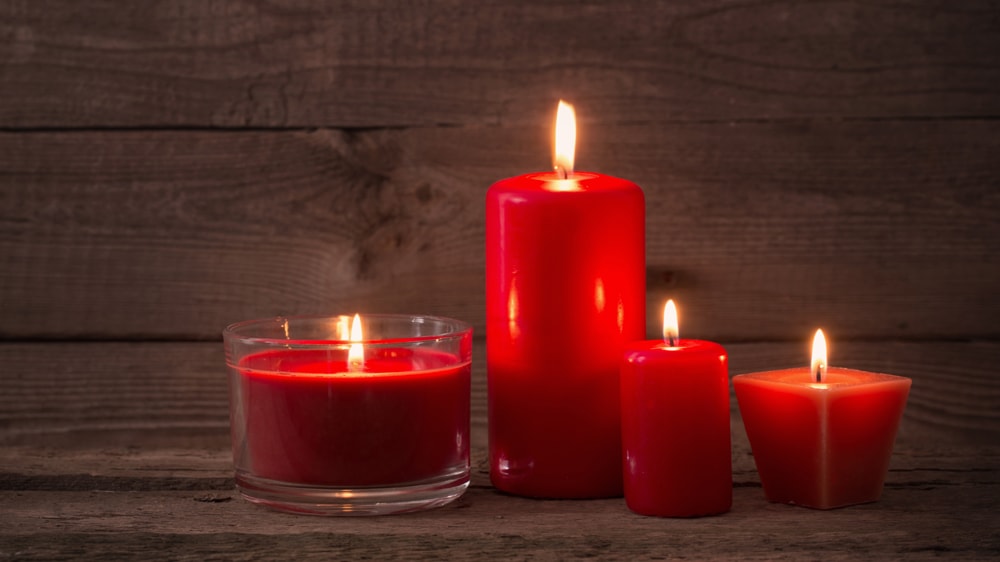 Four red candles in front of a wooden background