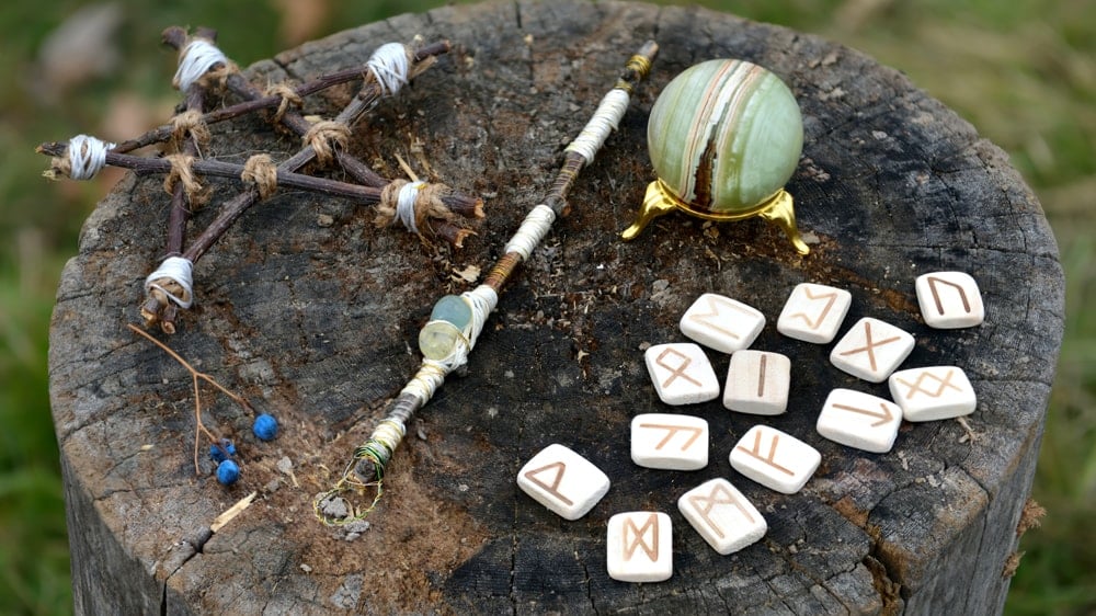 An altar on a wooden stump featuring a pentagram, a wand, runes, and a green sphere crystal