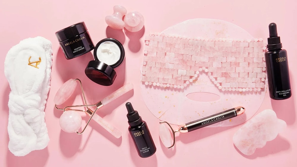 A collection of rose quartz beauty supplies on a pink background