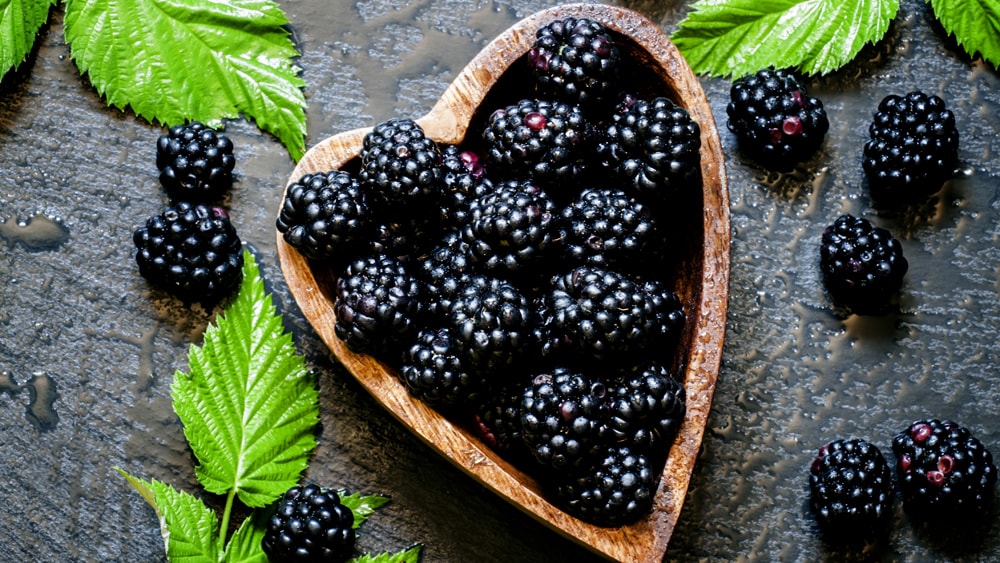 A heart shaped bowl of raspberries