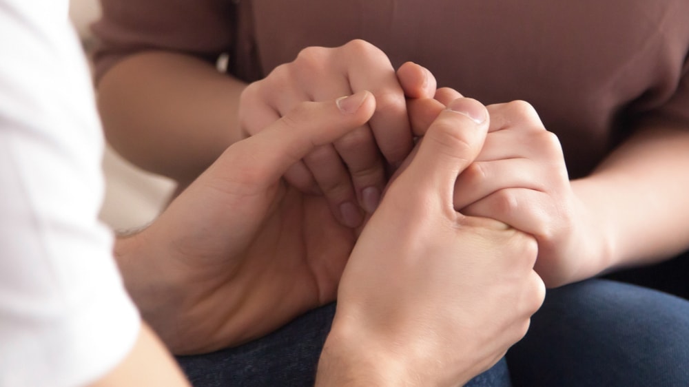 Hands of two people tightly joined to show love and compassion