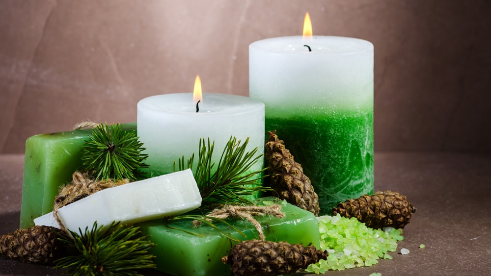 Green and white candles with evergreen branches and pine cones