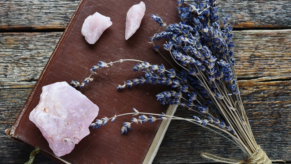 Rough rose quartz crystals and a bundle of lavender sprigs on an old book