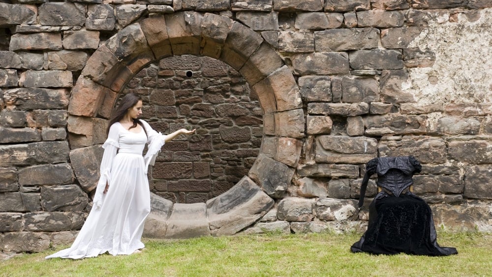 A woman in white in front of a stone wall