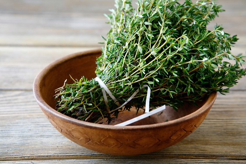 A bundle of fresh thyme in a wooden bowl