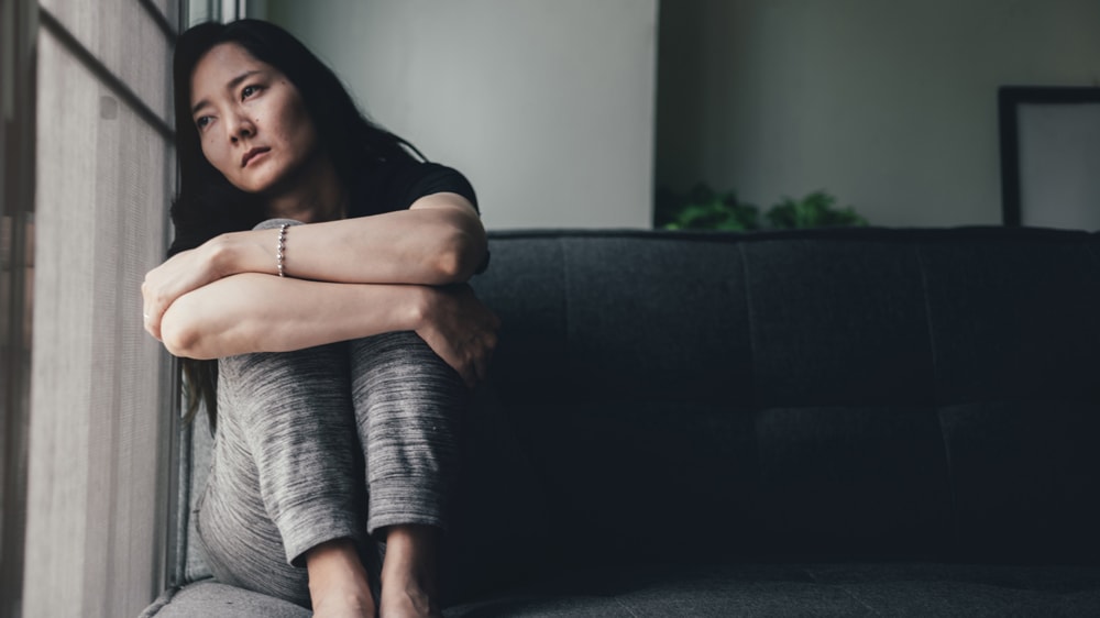 An anxious woman sitting by a window