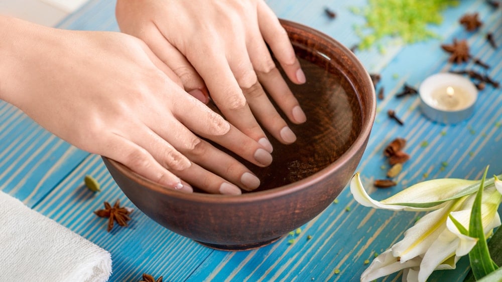 a woman dipping her fingers in a bowl of water