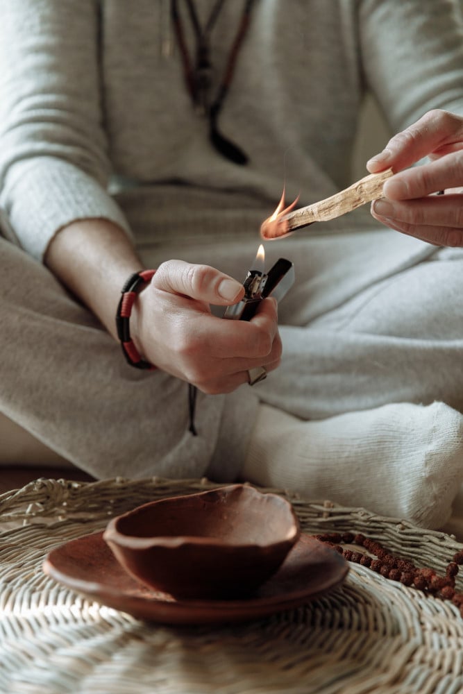 a man lighting a piece of Palo Santo wood for cleansing