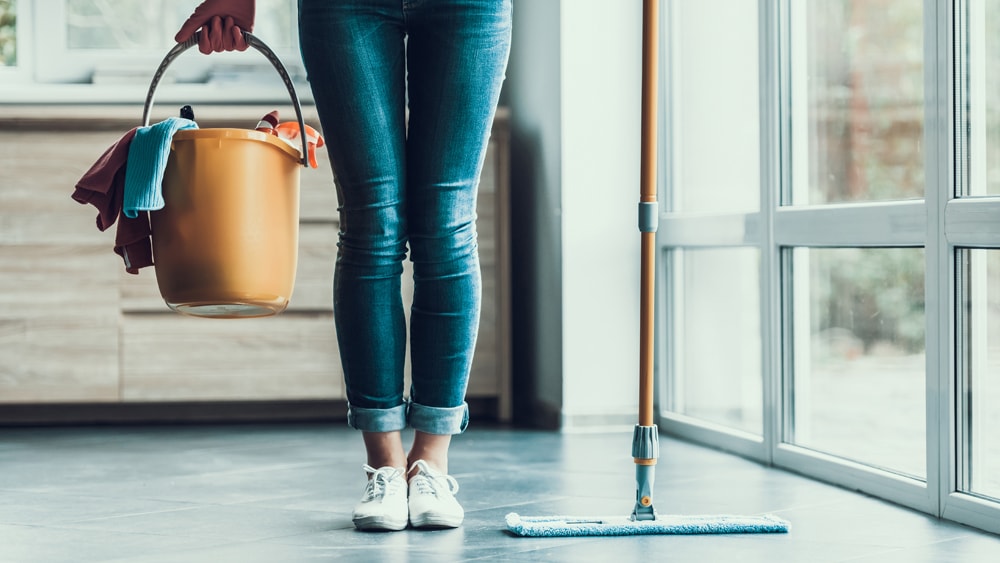 a woman holding cleaning supplies