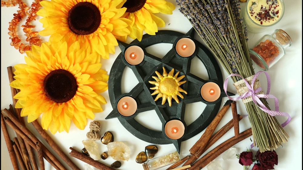 A Lammas altar featuring sunflowers, lavender, cinnamon, a pentacle, and orange candles