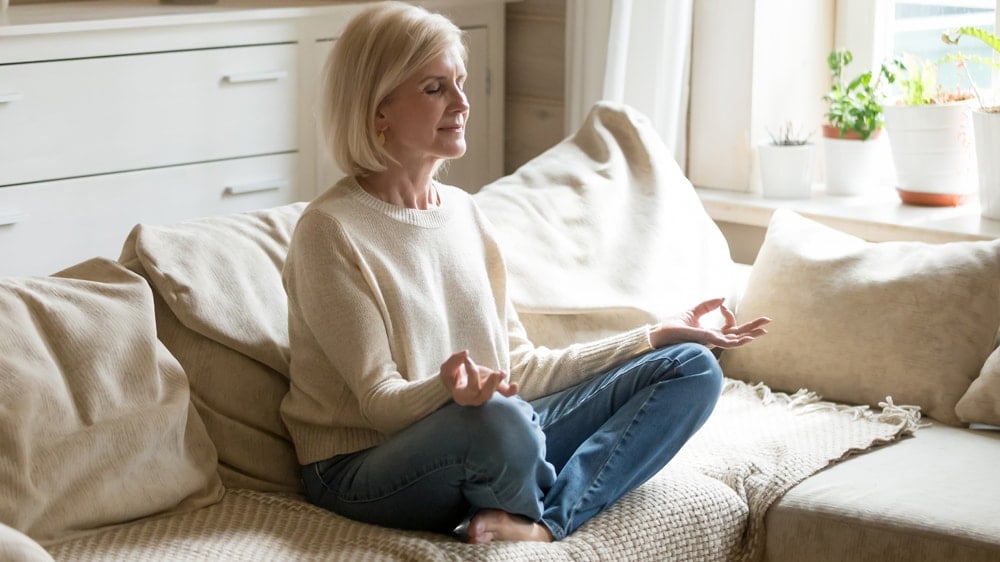 a woman meditating cross legged on a couch