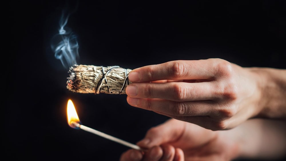 a person lighting a bundle of sage