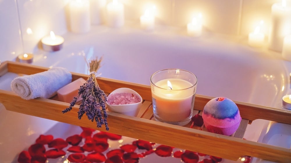 a bath with rose petals, lavender, rose quartz, candles, and a bath bomb
