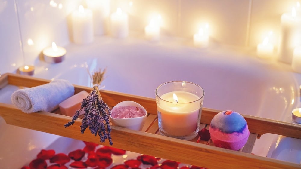 a bath with rose petals, lavender, rose quartz, candles, and a bath bomb