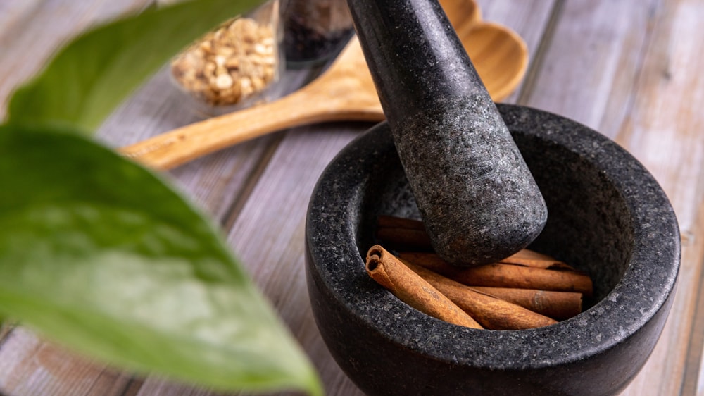 A mortar and pestle filled with cinnamon sticks