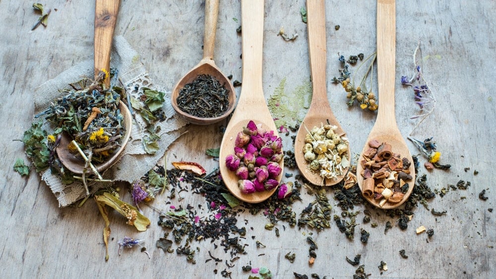 5 wooden spoons each filled with a different dried herb