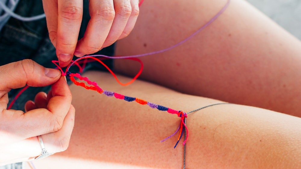 A girl braiding a friendship bracelet