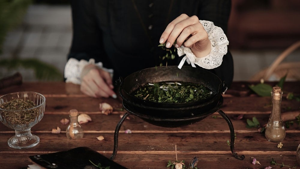 A woman dropping herbs into a bowl