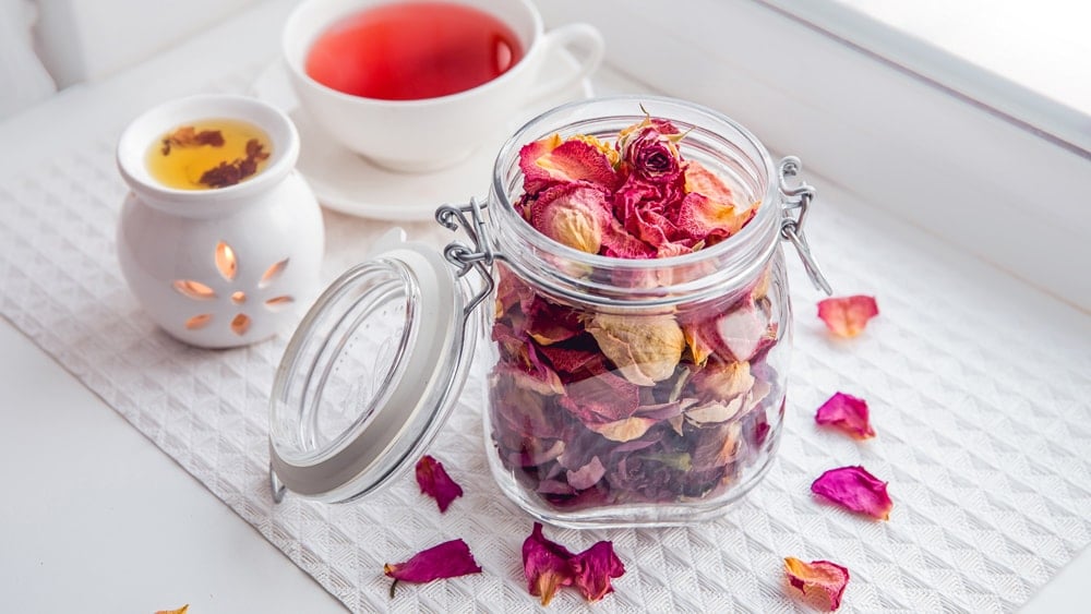 A jar of dried flowers beside a cup of tea