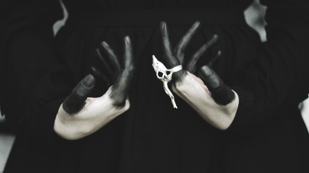 A witch with a skull ring and her fingers painted black