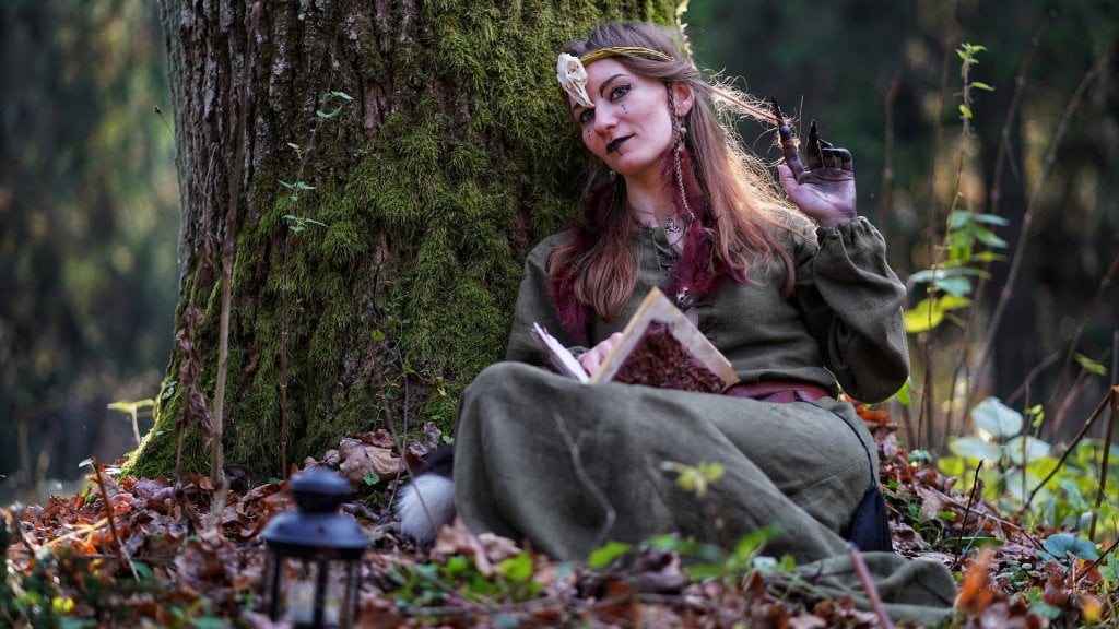 A woman in traditional dress reading in the forest