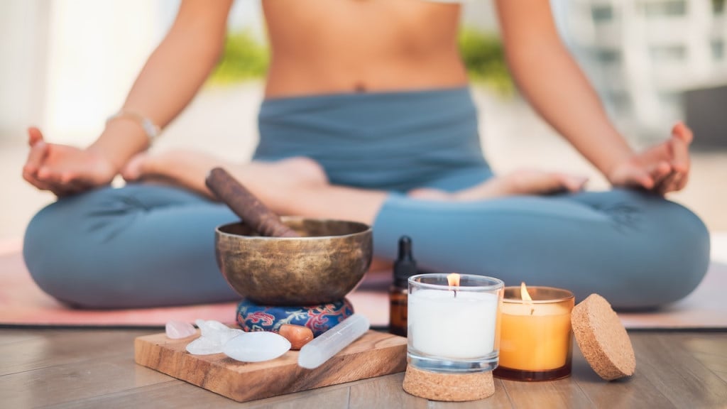 A woman practicing meditation with crystals, candles, and essential oils