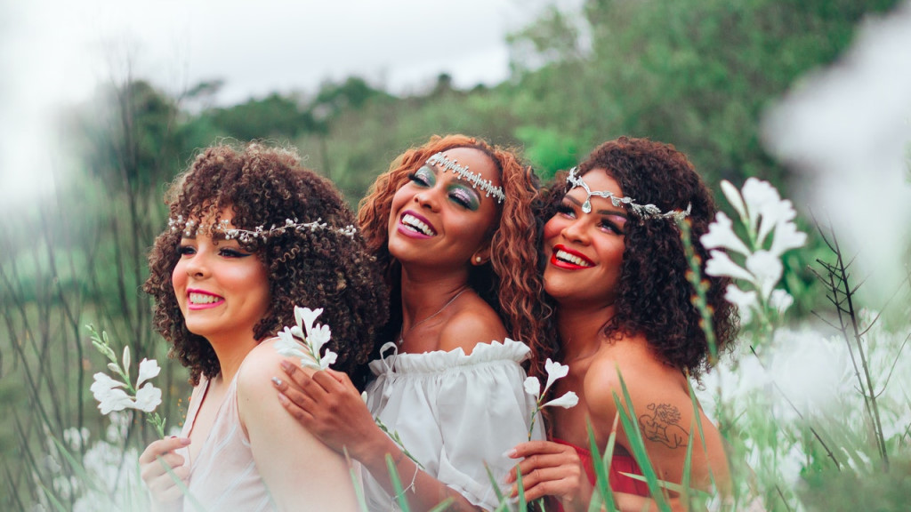 a group of three witches in a field of flowers