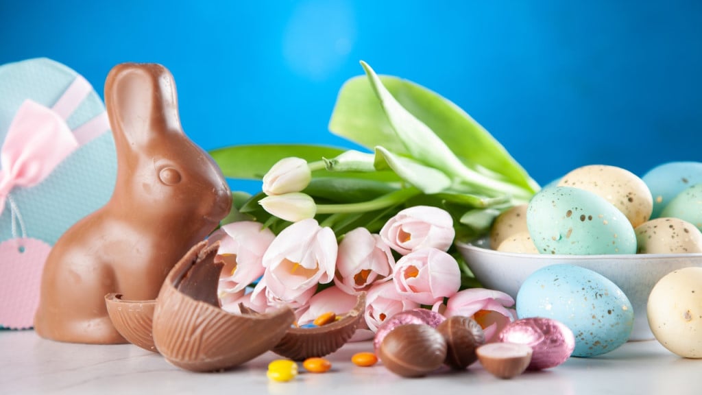 An assortment of Easter symbols: chocolate eggs, flowers, a chocolate bunny, and dyed eggs