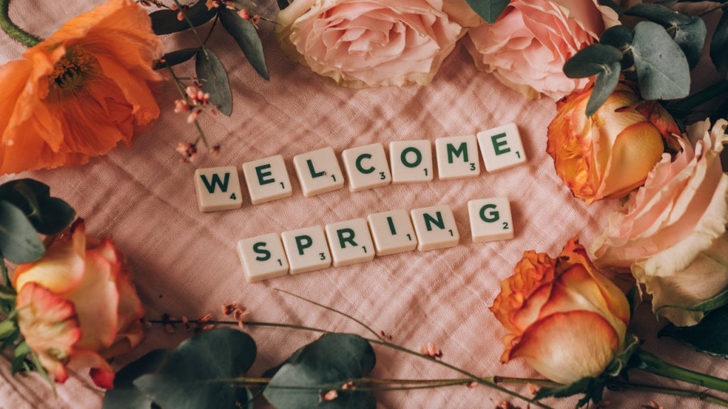 Welcome Spring spelled out with scrabble tiles among spring flowers