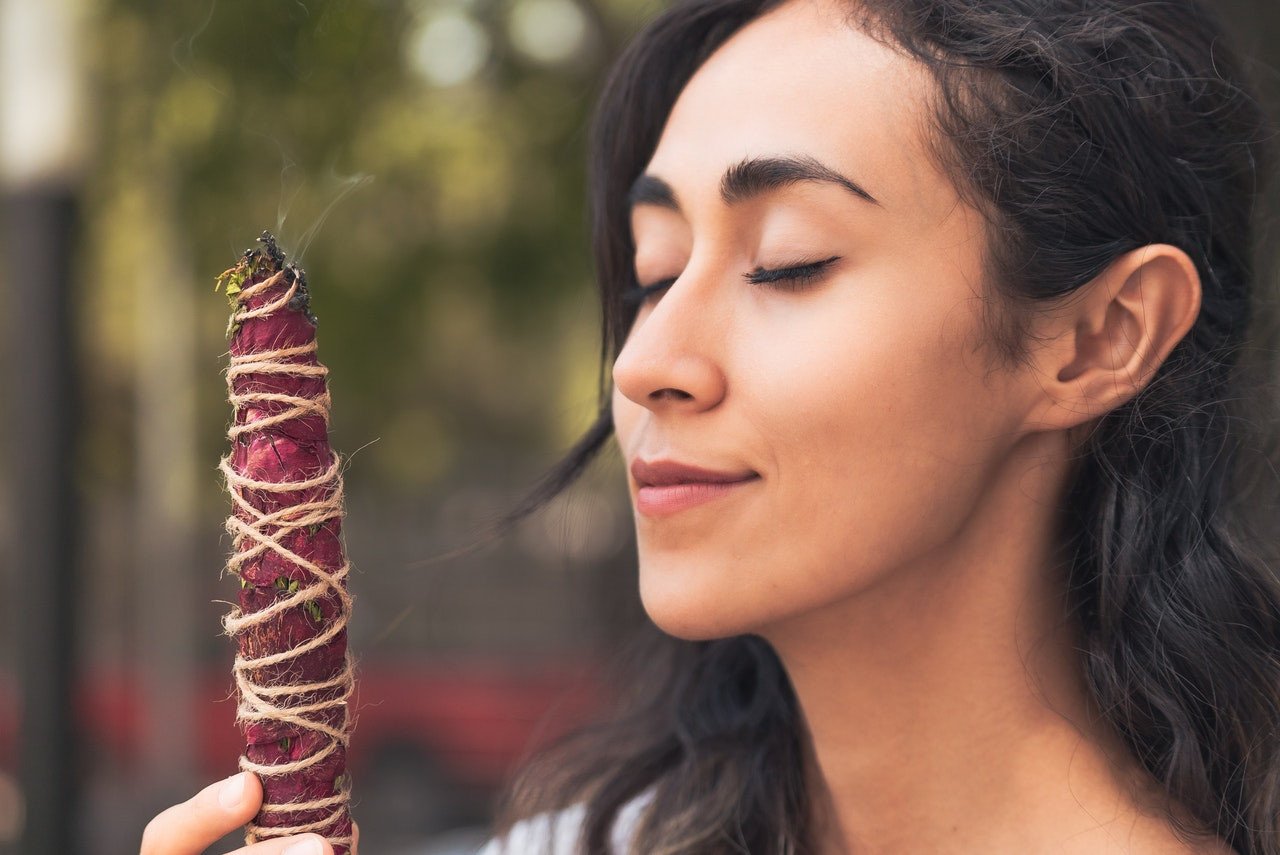 A woman burning a rose smudge stick