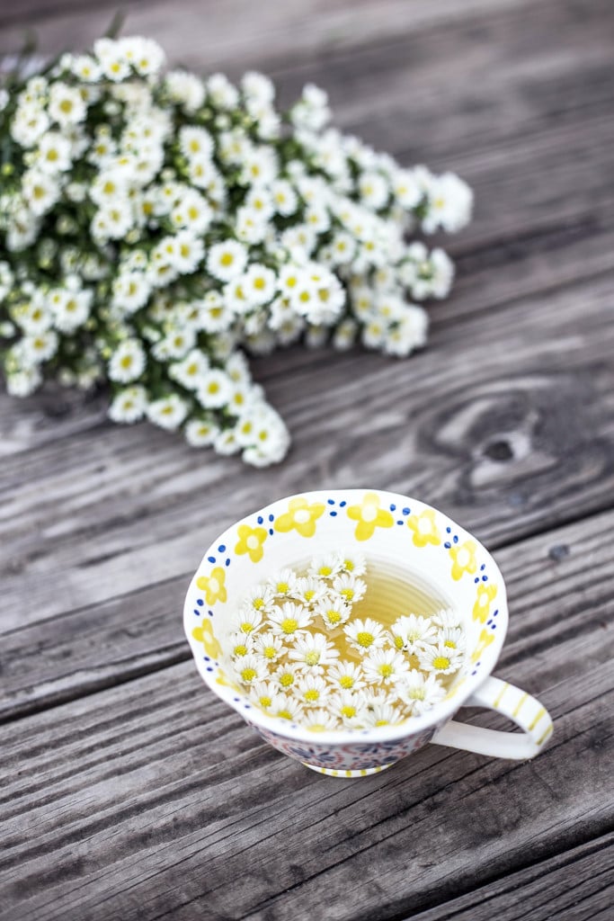 A cup of chamomile tea and beautiful chamomile flowers